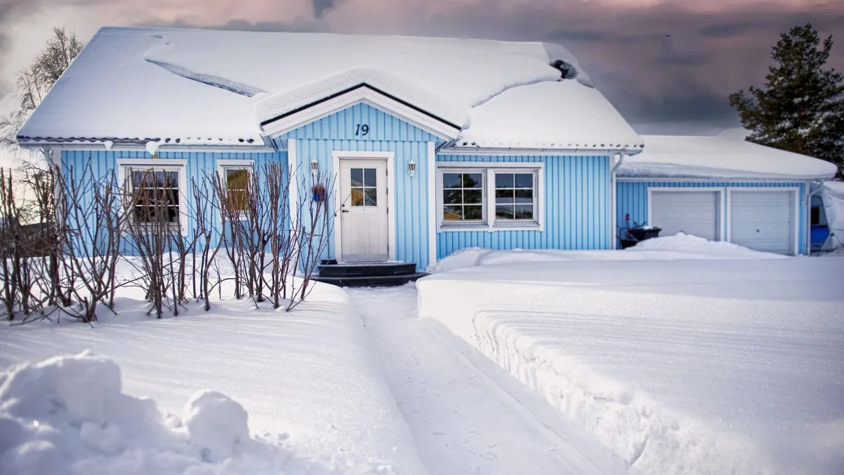 Snow-covered house roof in New Hampshire where ice dams form, a key topic in SEO for roofers in New Hampshire